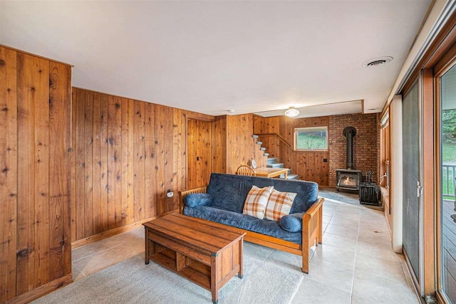3414 Reycraft Rd, Boyne City, MI 49712 - living area featuring stairway, a wood stove, wood walls, and light tile patterned flooring