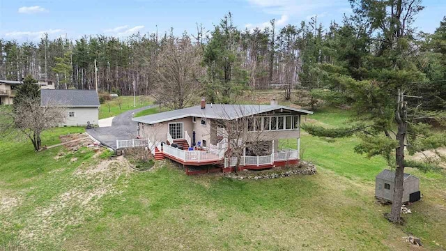 3414 Reycraft Rd, Boyne City, MI 49712 - rear view of property featuring a chimney, a sunroom, a wooden deck, a shed, and an outdoor structure
