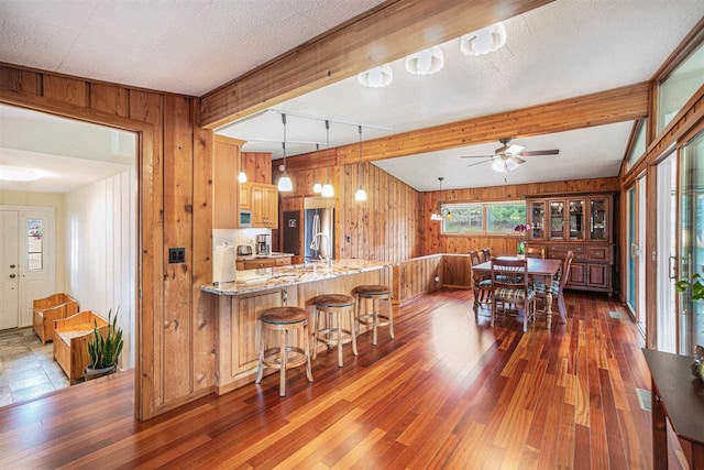 3414 Reycraft Rd, Boyne City, MI 49712 - kitchen featuring wood walls, hardwood / wood-style flooring, a ceiling fan, beam ceiling, and a peninsula