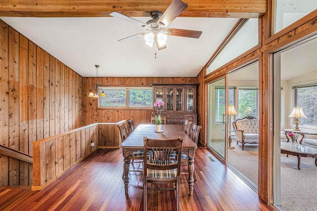 3414 Reycraft Rd, Boyne City, MI 49712 - dining space with lofted ceiling, wood walls, wood-type flooring, a ceiling fan, and a chandelier