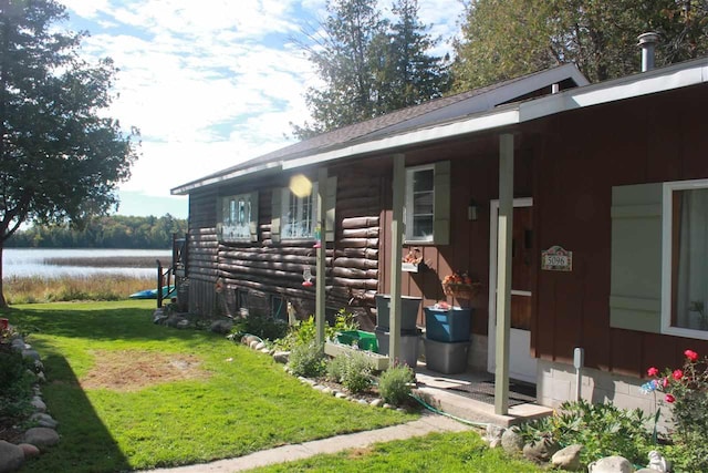 view of front of home with a water view, a front lawn, log siding, and a porch