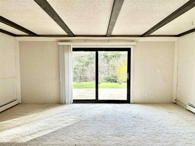 carpeted spare room featuring beamed ceiling and a textured ceiling