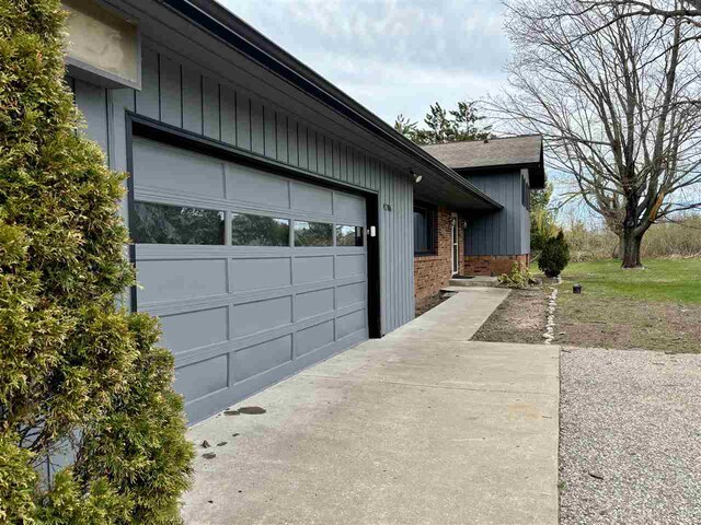 view of side of property with brick siding, concrete driveway, and a garage