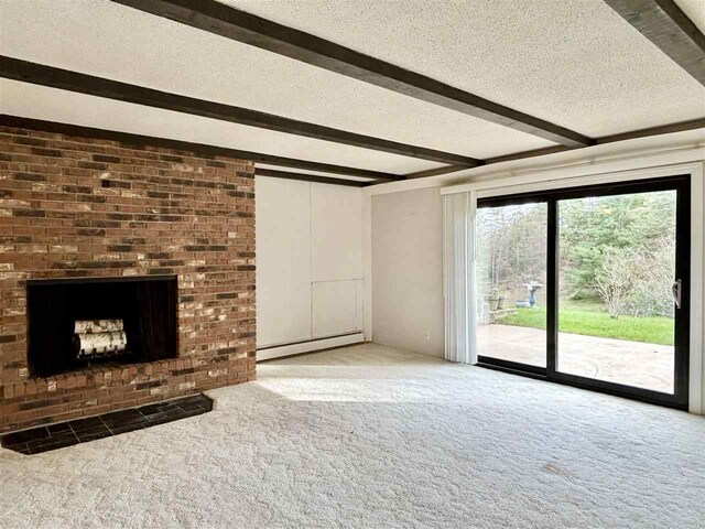 unfurnished living room featuring baseboard heating, carpet flooring, beam ceiling, a textured ceiling, and a fireplace