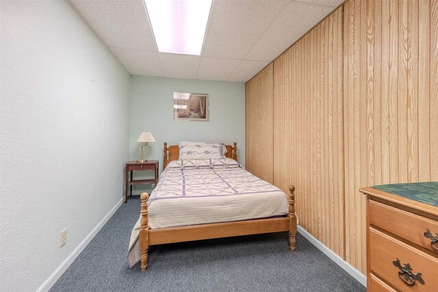 bedroom featuring carpet, a drop ceiling, and baseboards