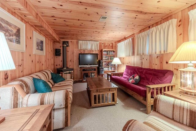 living room featuring wood walls, a wood stove, carpet, and wood ceiling