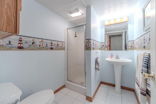full bath featuring toilet, a shower stall, tile patterned flooring, and a sink