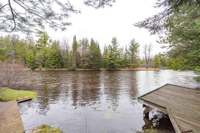 dock featuring a water view and a forest view