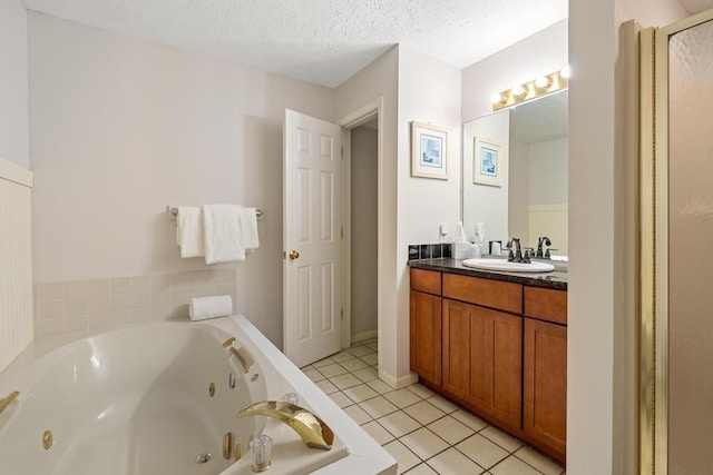 bathroom featuring tile patterned floors, a tub with jets, vanity, and a textured ceiling