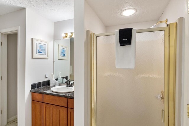 bathroom featuring a textured ceiling, a shower stall, vanity, and tile patterned floors