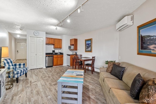 living area featuring a wall unit AC, a textured ceiling, light wood-style floors, rail lighting, and baseboards