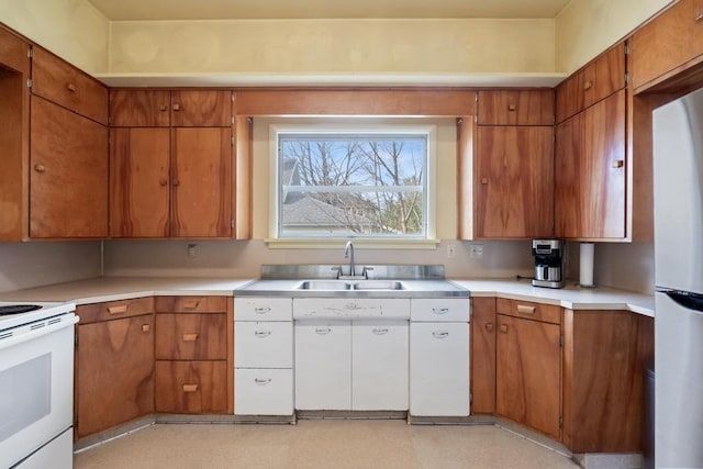 619 Kalamazoo Ave, Petoskey, MI 49770 - kitchen featuring electric stove, a sink, freestanding refrigerator, light countertops, and brown cabinetry