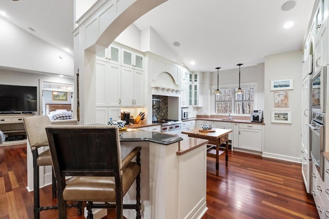 334 Birchwood Ter, Harbor Springs, MI 49740 - kitchen with a peninsula, glass insert cabinets, dark wood finished floors, white cabinetry, and hanging light fixtures