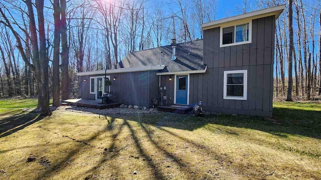 view of front of property featuring roof with shingles, board and batten siding, a front lawn, and a chimney