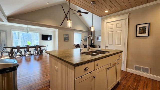kitchen with a sink, a ceiling fan, vaulted ceiling, a center island with sink, and pendant lighting