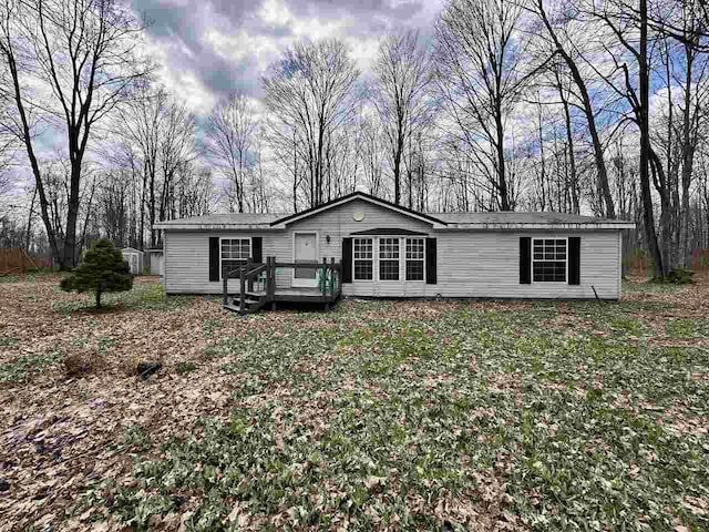 4049 Musser Rd, Mancelona, MI 49659 - manufactured / mobile home featuring a deck, view of wooded area, and a front yard