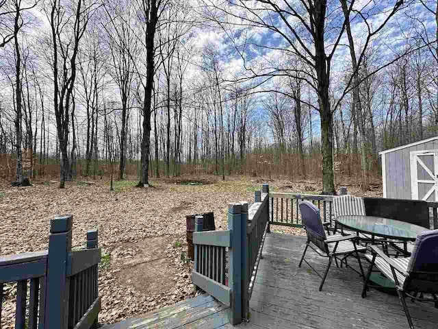 4049 Musser Rd, Mancelona, MI 49659 - deck featuring outdoor dining area, a shed, and an outbuilding