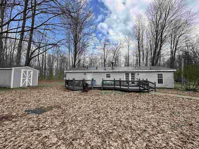 4049 Musser Rd, Mancelona, MI 49659 - rear view of property with a storage shed, an outbuilding, a wooden deck, and view of wooded area