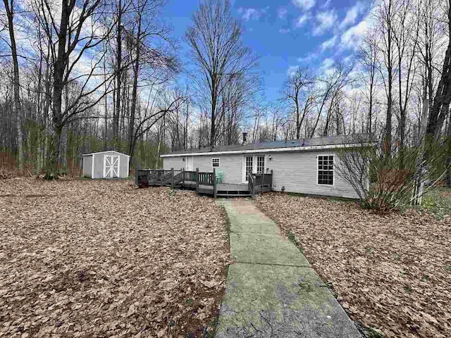 4049 Musser Rd, Mancelona, MI 49659 - manufactured / mobile home with a wooden deck, a storage unit, and an outdoor structure