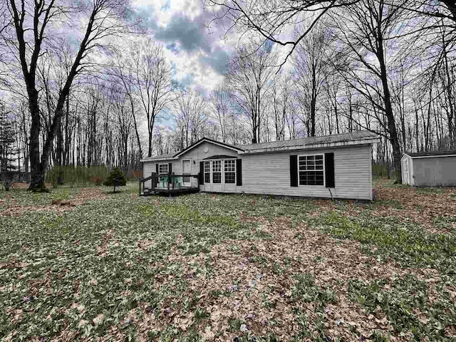 4049 Musser Rd, Mancelona, MI 49659 - manufactured / mobile home featuring a storage shed, an outbuilding, a deck, and a front lawn