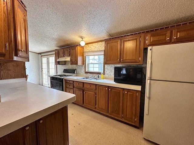 4049 Musser Rd, Mancelona, MI 49659 - kitchen with freestanding refrigerator, range with gas cooktop, black microwave, under cabinet range hood, and a sink
