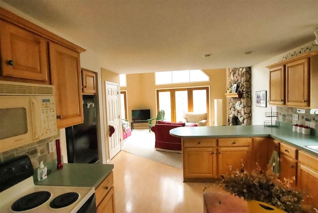 3330 Commodore Dr, East Jordan, MI 49727 - kitchen with white microwave, range with electric stovetop, black refrigerator, a stone fireplace, and a peninsula