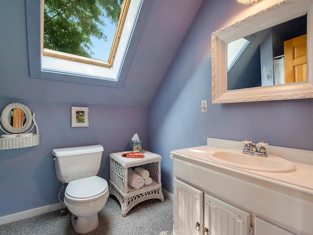 101 S Addis Rd, Boyne City, MI 49712 - bathroom featuring a skylight, toilet, vanity, lofted ceiling, and baseboards