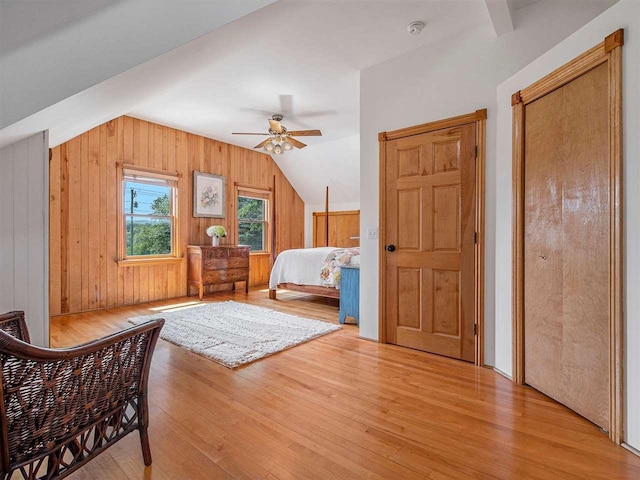 101 S Addis Rd, Boyne City, MI 49712 - bedroom featuring light wood-style floors, vaulted ceiling, wood walls, and ceiling fan