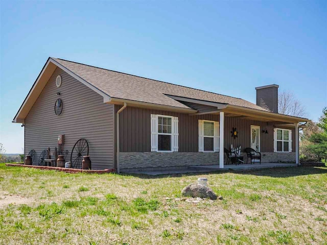 10300 Vista Ridge Dr, Alden, MI 49612 - view of side of home featuring a chimney, stone siding, board and batten siding, a yard, and a shingled roof