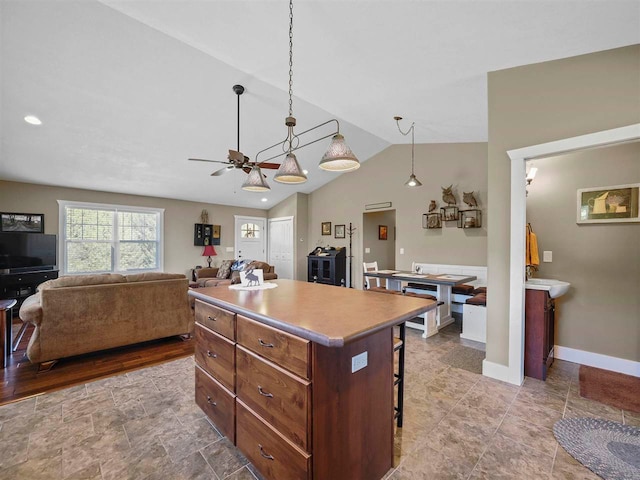 10300 Vista Ridge Dr, Alden, MI 49612 - kitchen featuring a kitchen breakfast bar, vaulted ceiling, a kitchen island, a ceiling fan, and decorative light fixtures
