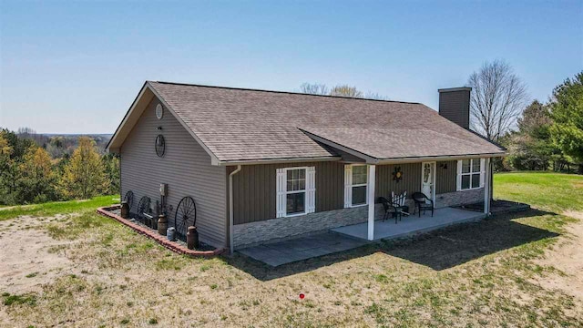 10300 Vista Ridge Dr, Alden, MI 49612 - back of house with a chimney, a patio, a lawn, stone siding, and roof with shingles