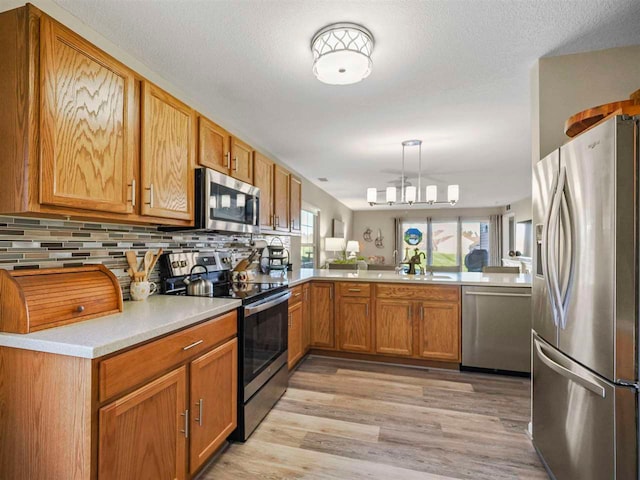 1564 Emerald Ct Unit 85, Petoskey, MI 49770 - kitchen with stainless steel appliances, a peninsula, decorative backsplash, light wood-style floors, and light countertops