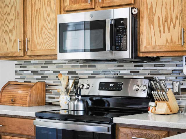 1564 Emerald Ct Unit 85, Petoskey, MI 49770 - kitchen with stainless steel appliances, tasteful backsplash, light countertops, and brown cabinets