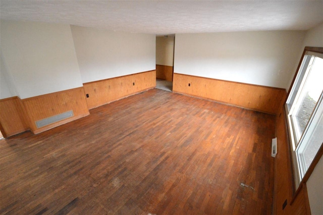 409 Trent St, Boyne City, MI 49712 - empty room with wainscoting, wooden walls, wood finished floors, and a textured ceiling