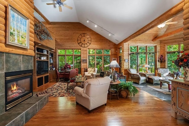 1442 Indian Point Rd, Brutus, MI 49716 - living room with wood finished floors, high vaulted ceiling, a ceiling fan, a fireplace, and log walls
