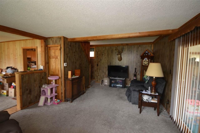 living area with wooden walls, carpet flooring, a textured ceiling, and beamed ceiling