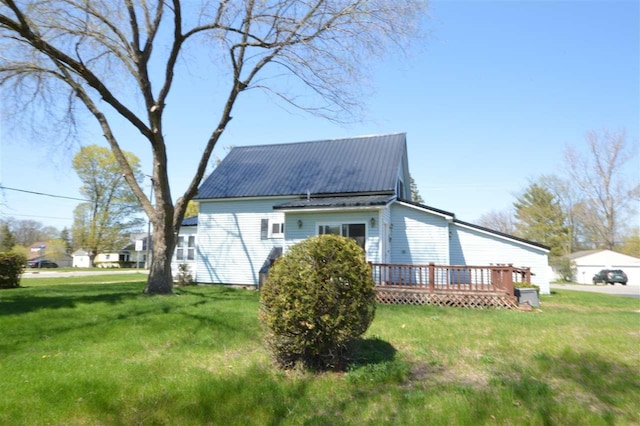 rear view of property featuring metal roof, a deck, and a lawn