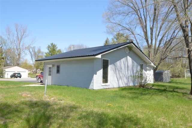 view of side of property featuring an outdoor structure, a garage, and a yard