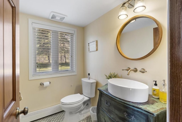 half bathroom featuring a baseboard heating unit, tile patterned flooring, toilet, vanity, and baseboards