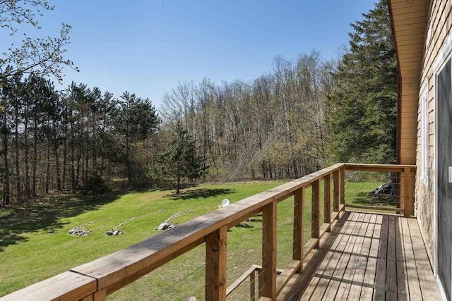 deck featuring a lawn and a wooded view