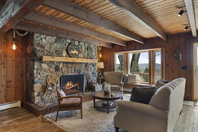 living room featuring beamed ceiling, wood-type flooring, wooden ceiling, wooden walls, and a stone fireplace
