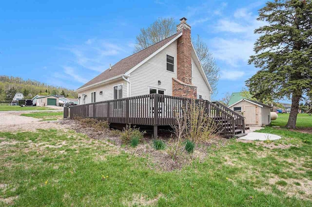 3190 Spring Dr, Boyne Falls, MI 49713 - rear view of house featuring a wooden deck, a chimney, a lawn, and a shingled roof