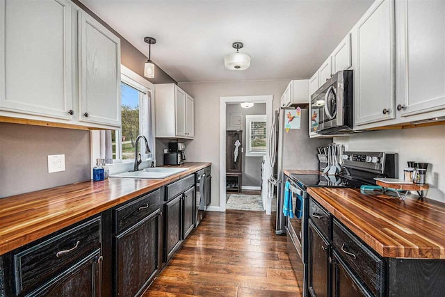 3190 Spring Dr, Boyne Falls, MI 49713 - kitchen featuring butcher block countertops, stainless steel appliances, a sink, dark wood-style flooring, and white cabinets
