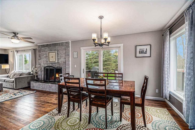 3190 Spring Dr, Boyne Falls, MI 49713 - dining space with dark wood-style flooring, a chandelier, a brick fireplace, ceiling fan, and baseboards