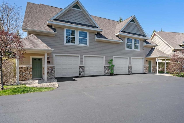 4070 Carriage House Dr Unit 5 & 6, Bay Harbor, MI 49770 - view of front of house featuring an attached garage, stone siding, asphalt driveway, and roof with shingles