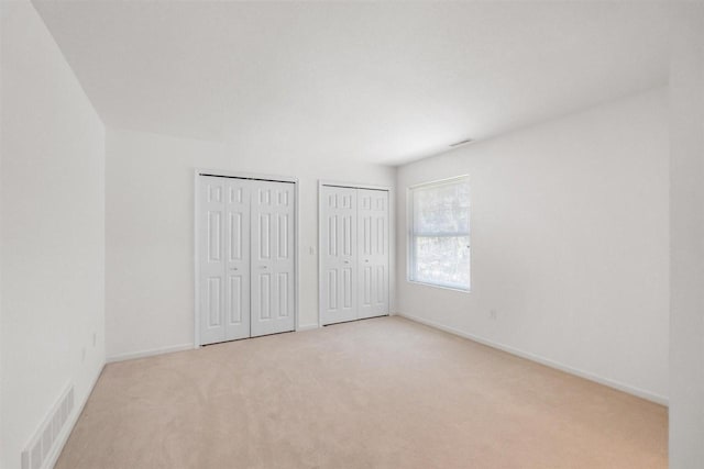 4070 Carriage House Dr Unit 5 & 6, Bay Harbor, MI 49770 - unfurnished bedroom featuring two closets, carpet flooring, and baseboards