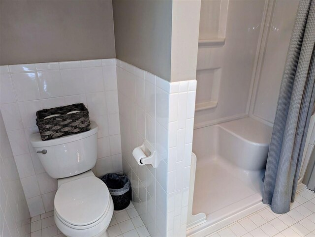 5350 Golfview Rd, Bellaire, MI 49615 - bathroom with tile walls, a stall shower, toilet, and tile patterned flooring