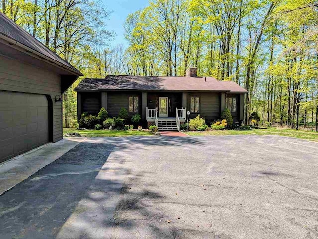 5350 Golfview Rd, Bellaire, MI 49615 - ranch-style house featuring a porch, a chimney, a garage, and driveway