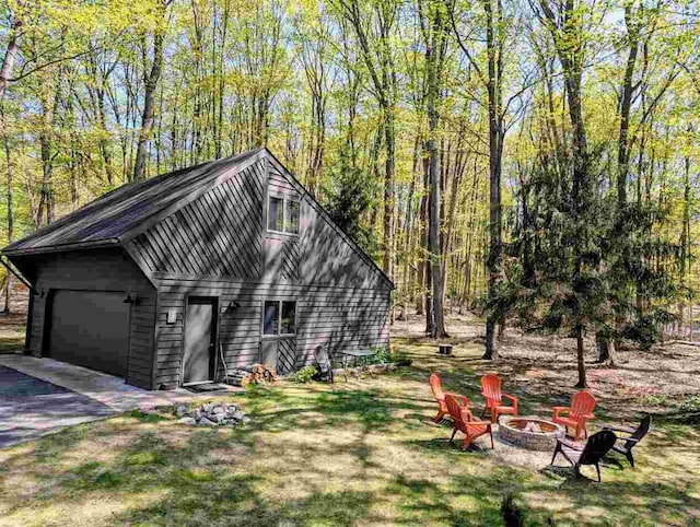 5350 Golfview Rd, Bellaire, MI 49615 - view of front of property featuring an outdoor fire pit, a garage, and a view of trees