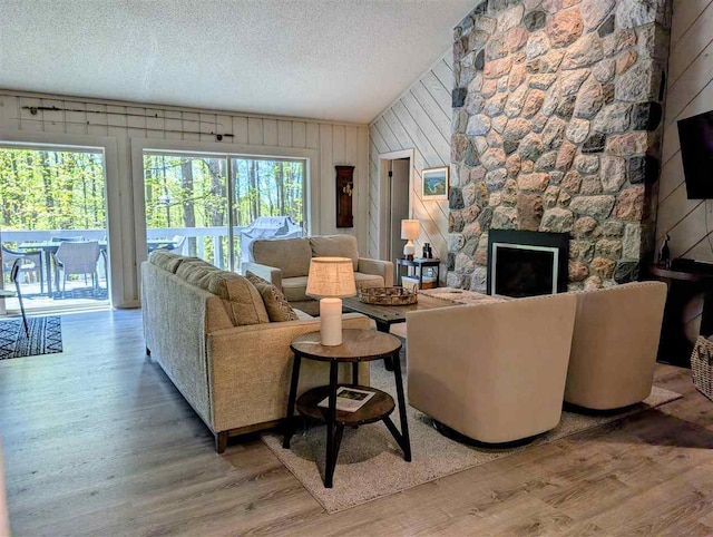 5350 Golfview Rd, Bellaire, MI 49615 - living room featuring wood finished floors, wood walls, a textured ceiling, a fireplace, and vaulted ceiling